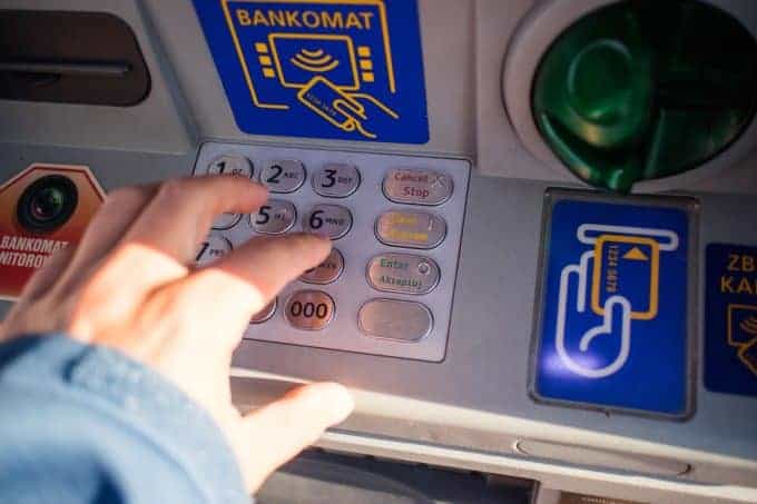 osoba, wybierająca pieniądze z bankomatu